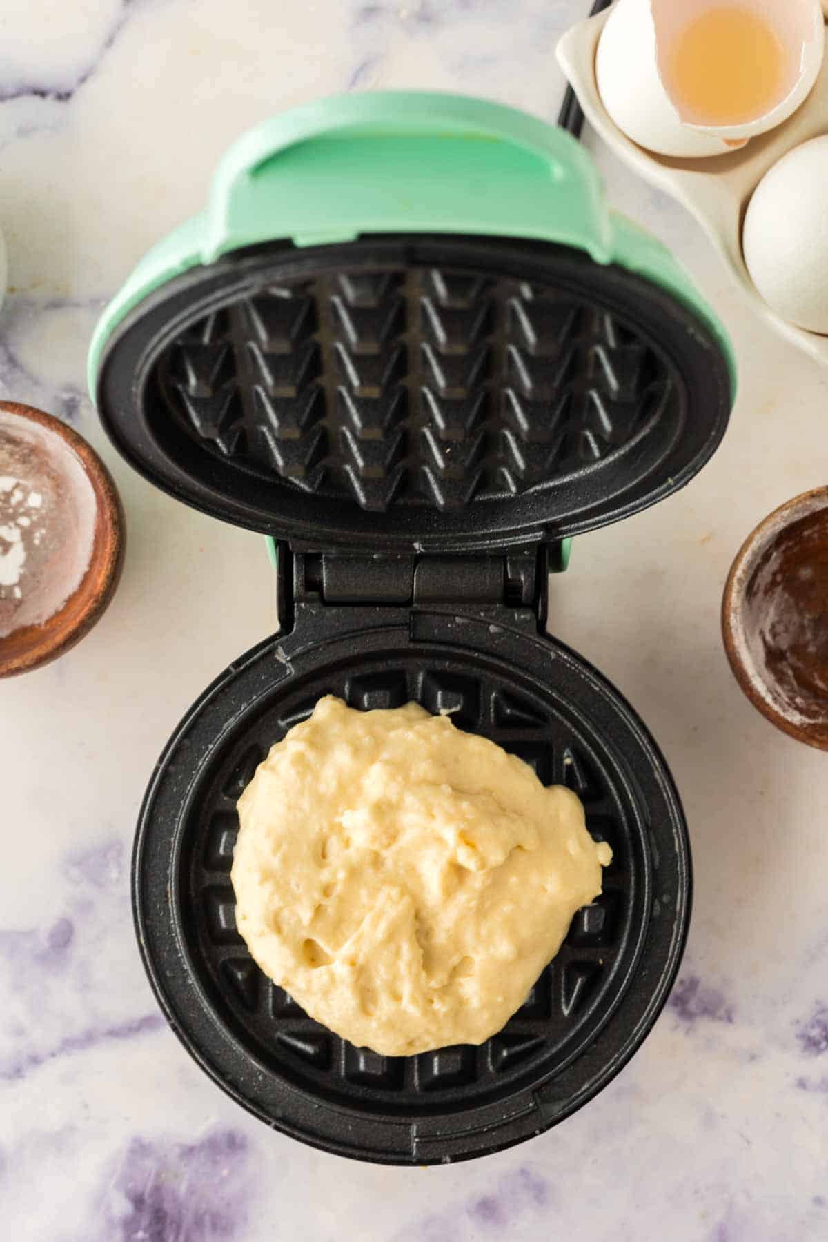 top view of a waffle iron and the batter going in