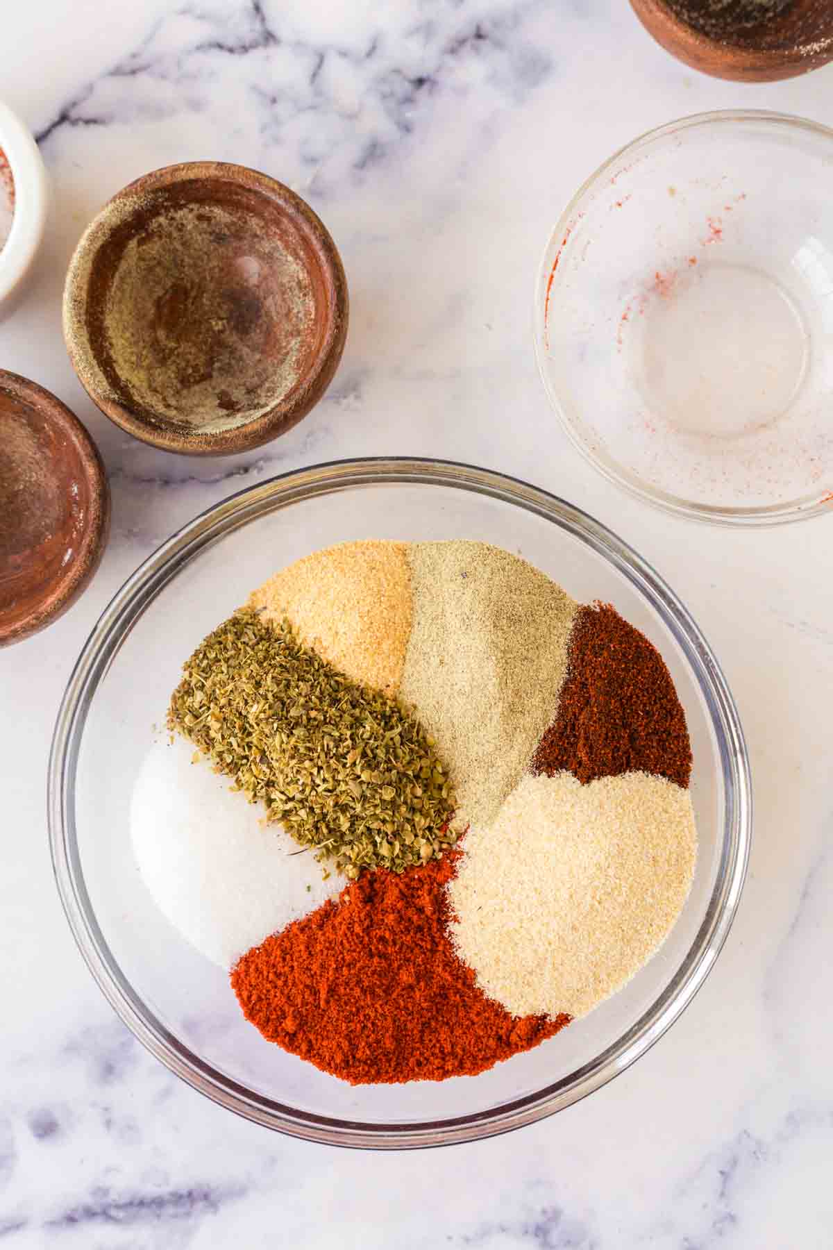 white mixing bowl with all the colors of cajun seasoning before being mixed