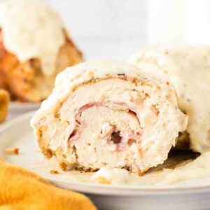 end view sliced chicken cordon bleu roll browned to a golden crunchy smothered in sauce on a plate