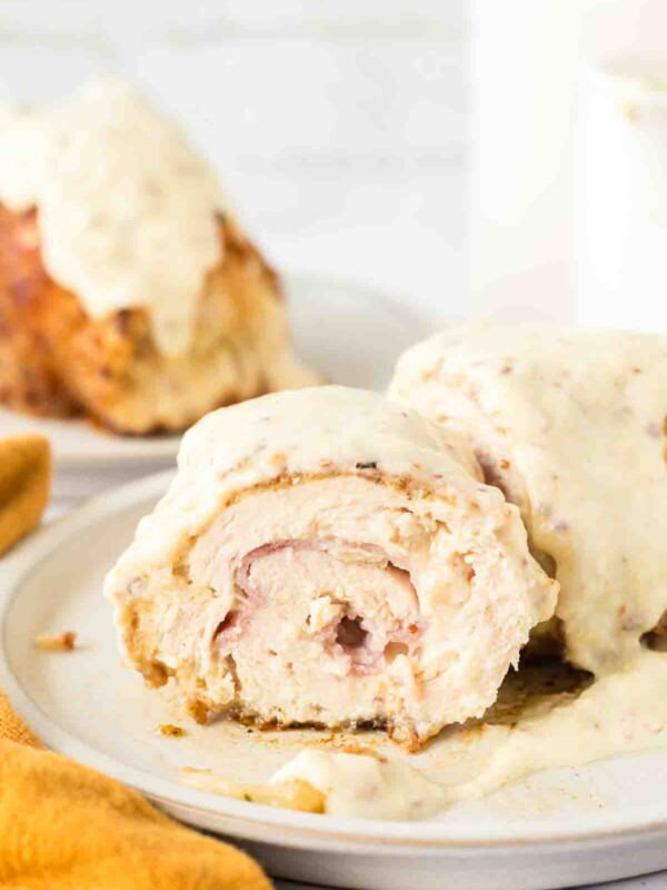 end view sliced chicken cordon bleu roll browned to a golden crunchy smothered in sauce on a plate