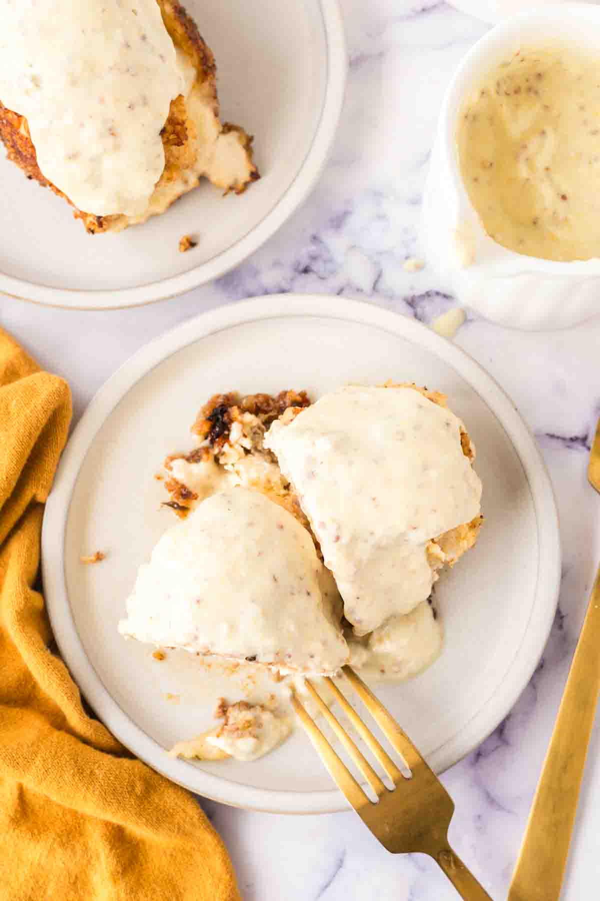 top view of a sliced chicken cordon bleu roll browned to a golden crunchy smothered in sauce on a plate