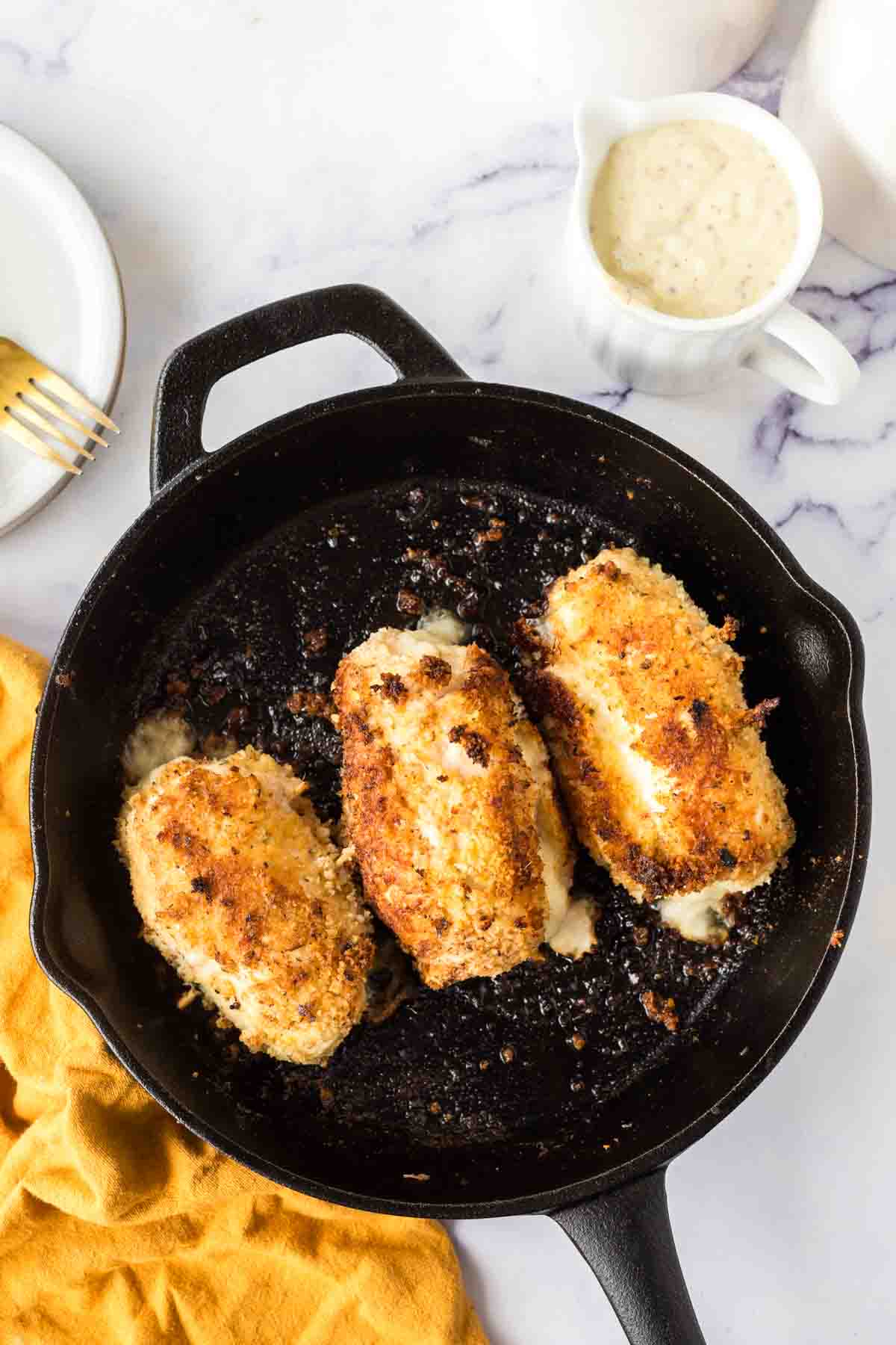 chicken cordon bleu roll browned to a golden crunchy in a cast iron pan