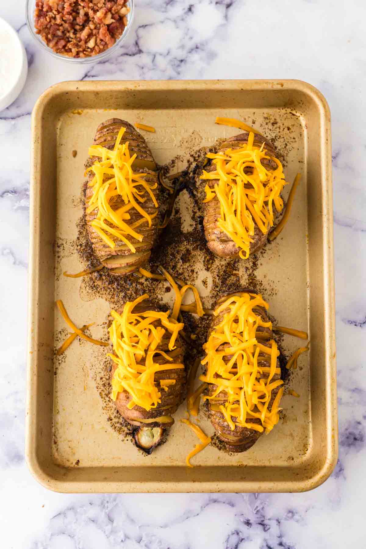 hasselback potatoes on a baking sheet with cheese