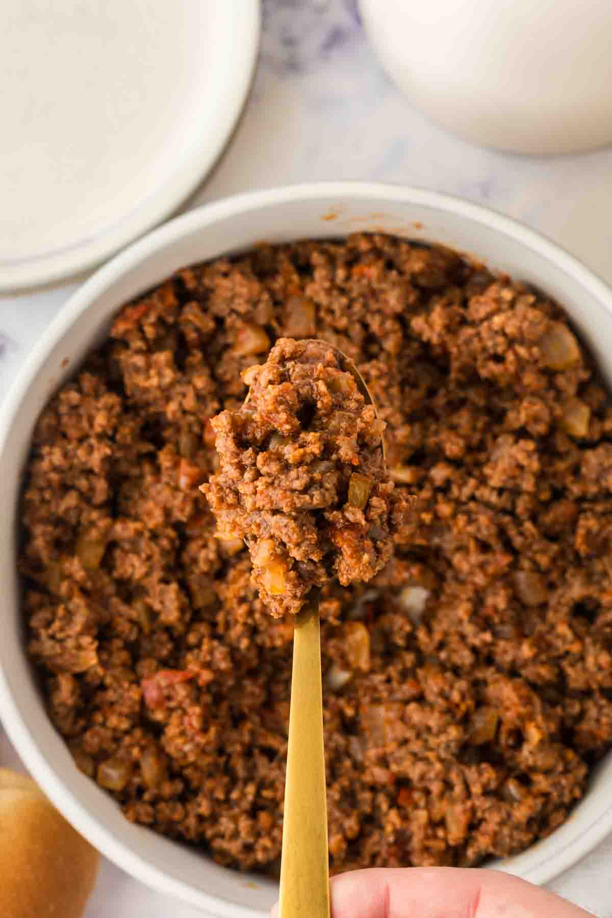 top view of hot dog chili recipe in a bowl next to some buns