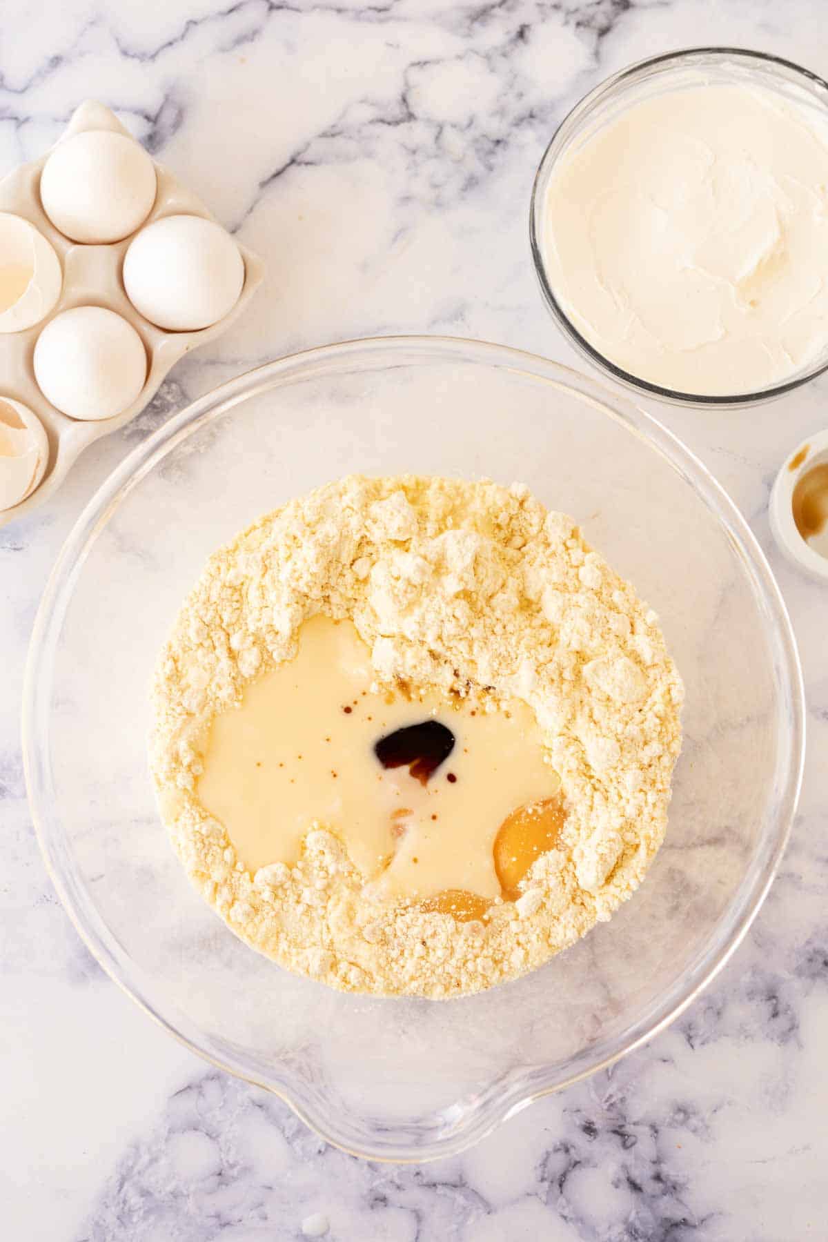 clear mixing bowl with stages of raw ugly cake ingredients