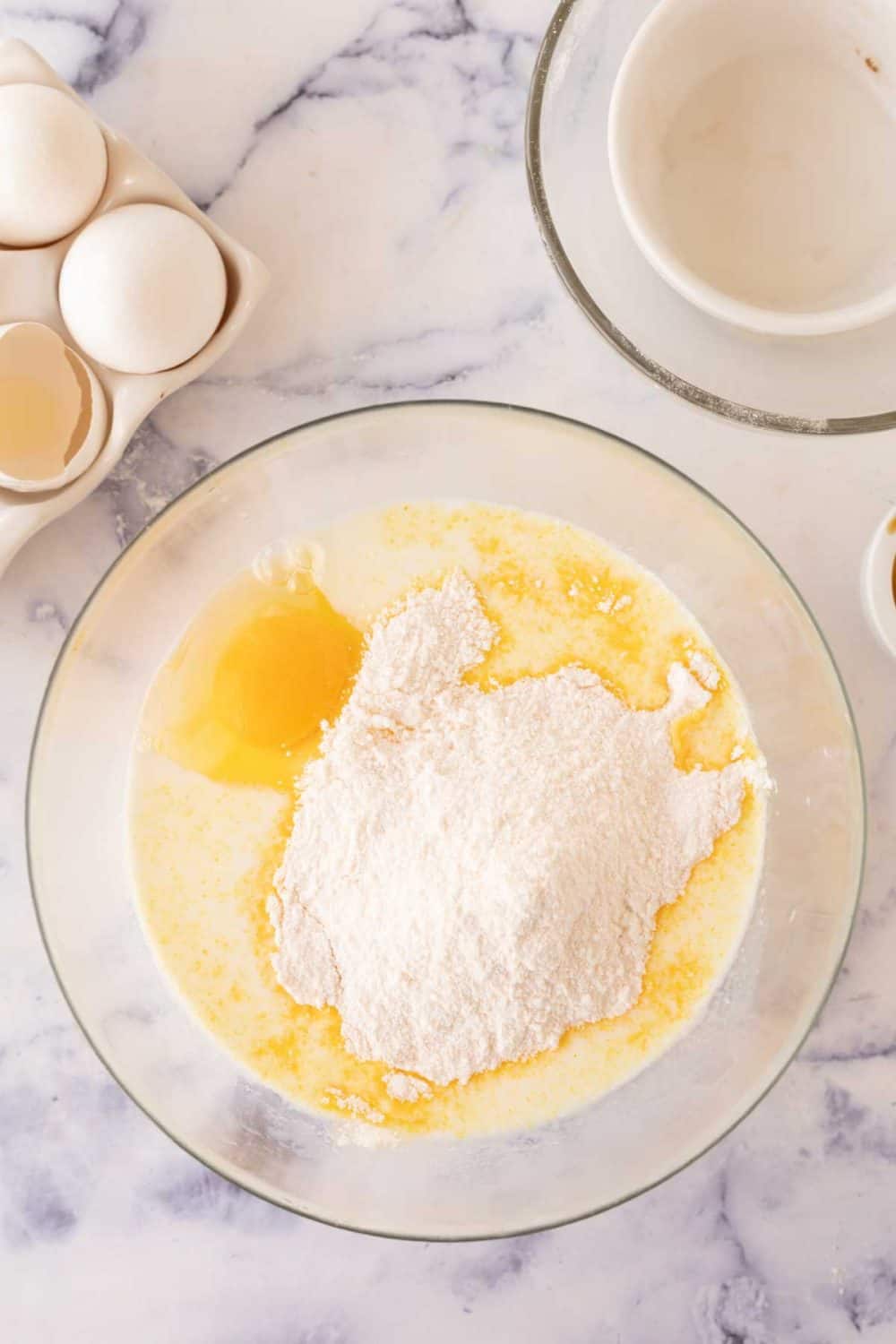 clear mixing bowl with stages of raw ugly cake ingredients