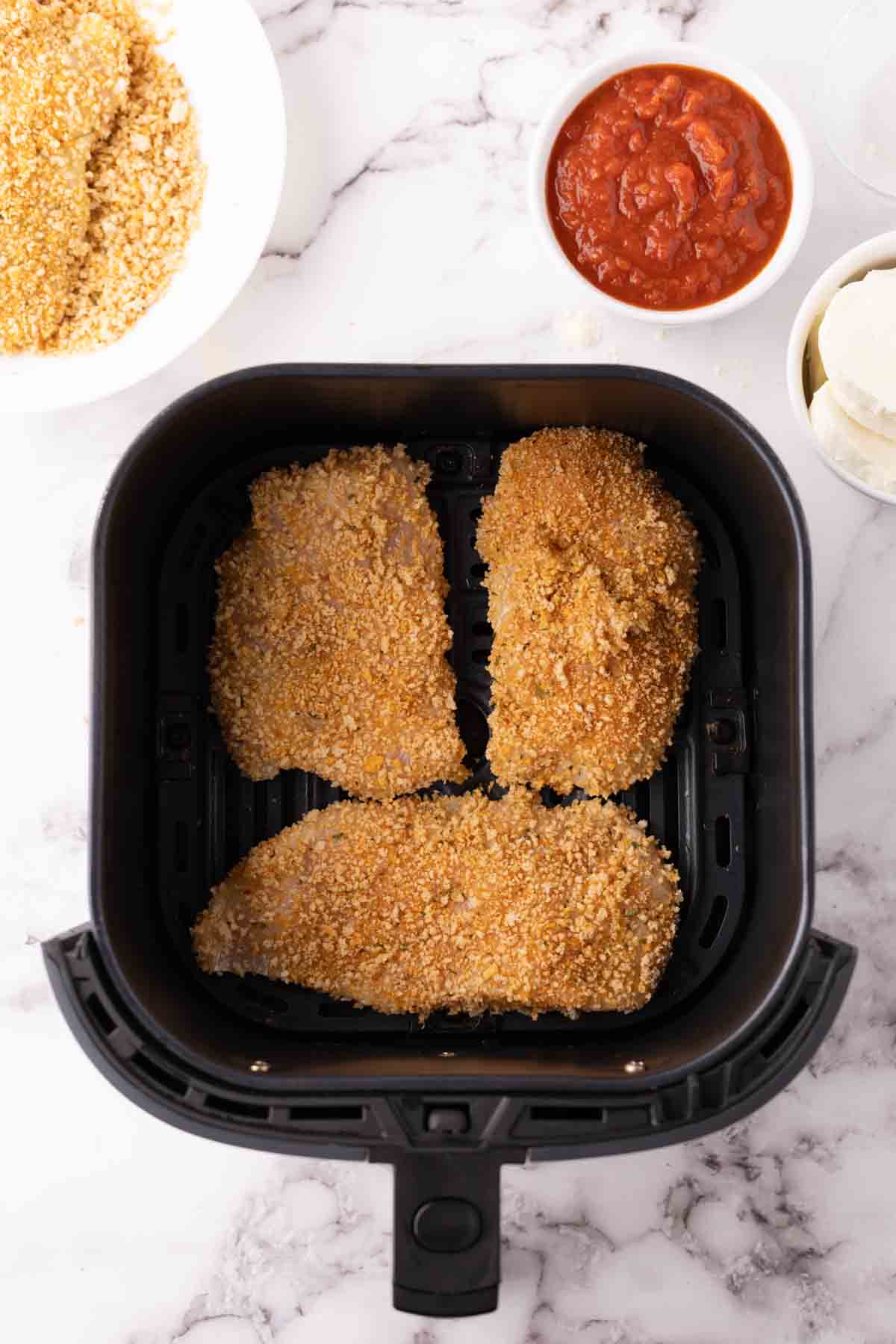 crispy air fried chicken tenders in a black air fryer basket.
