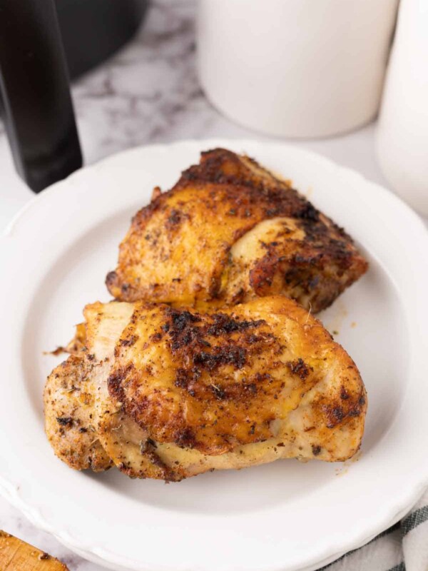 air fried crispy skinned chicken thighs on a white plate.