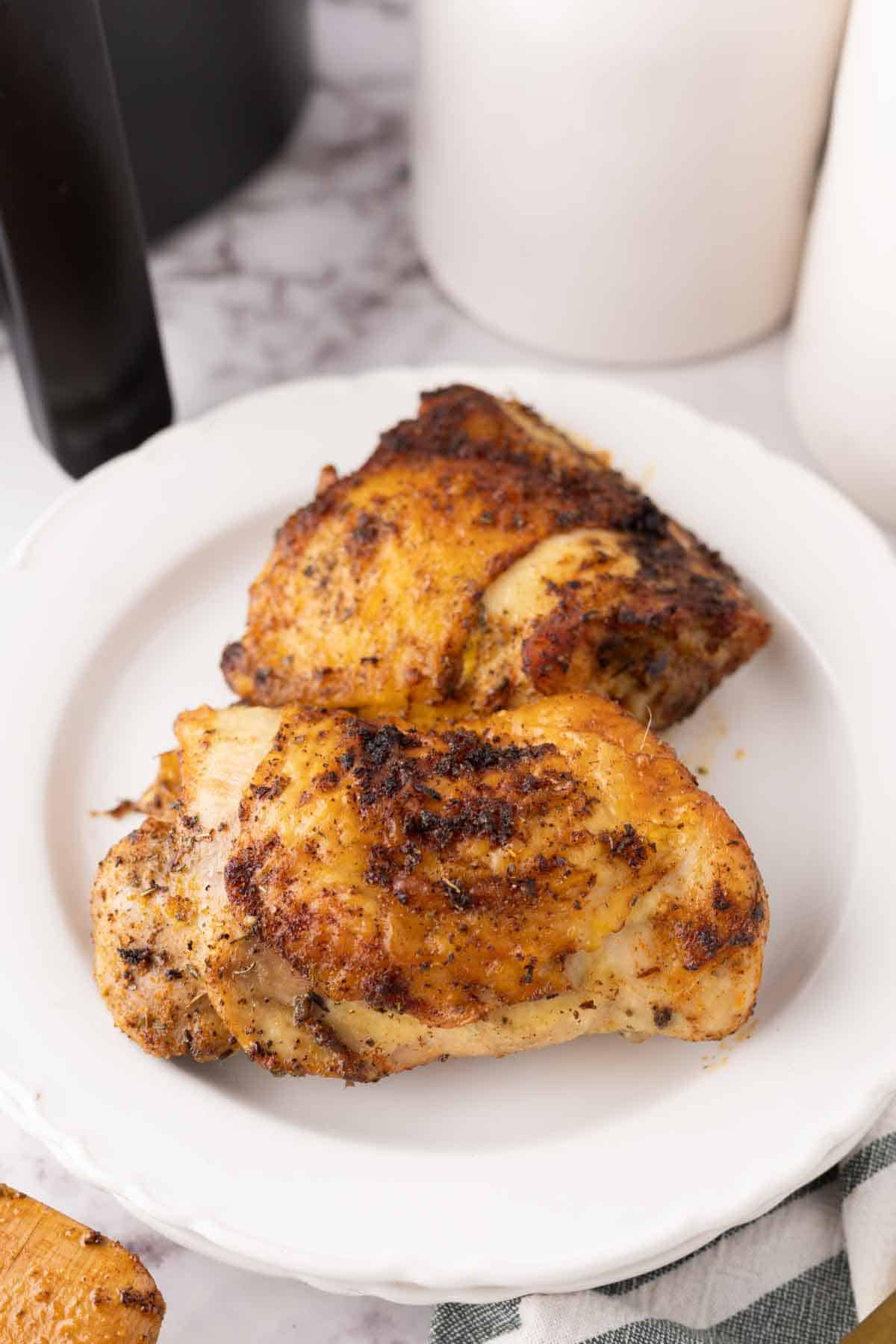 air fried crispy skinned chicken thighs on a white plate.