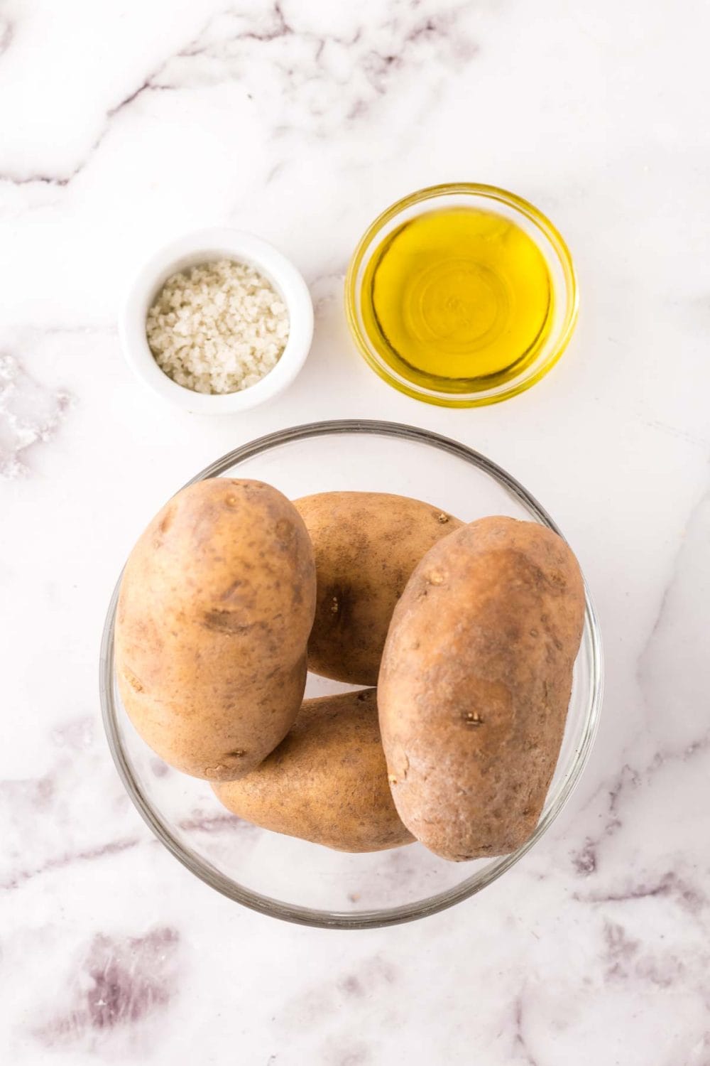 mixing bowl and portion bowls each with raw ingredient to make air fryer potato chips.