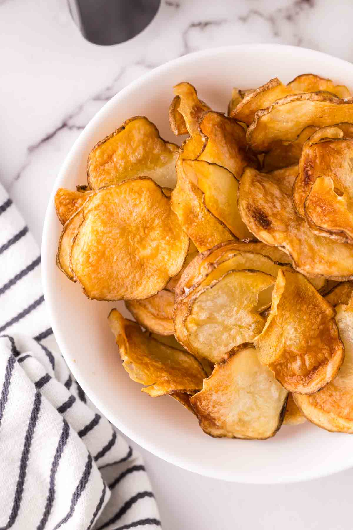 air fried potato chips in a white bowl.