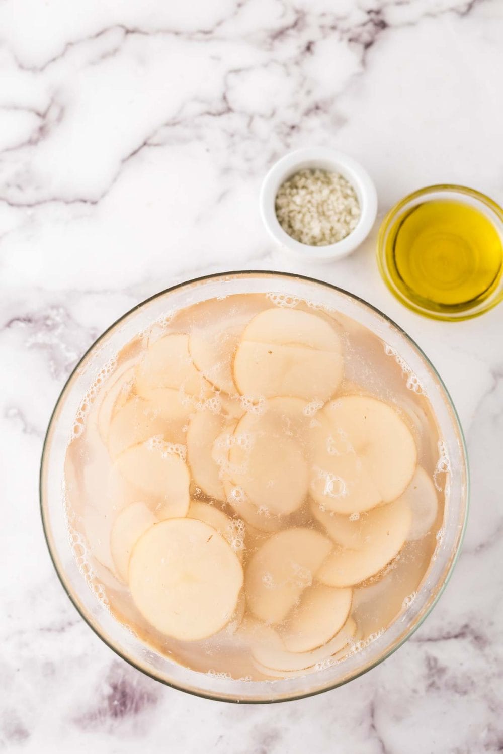 mixing bowl and portion bowls each with raw ingredient to make air fryer potato chips.