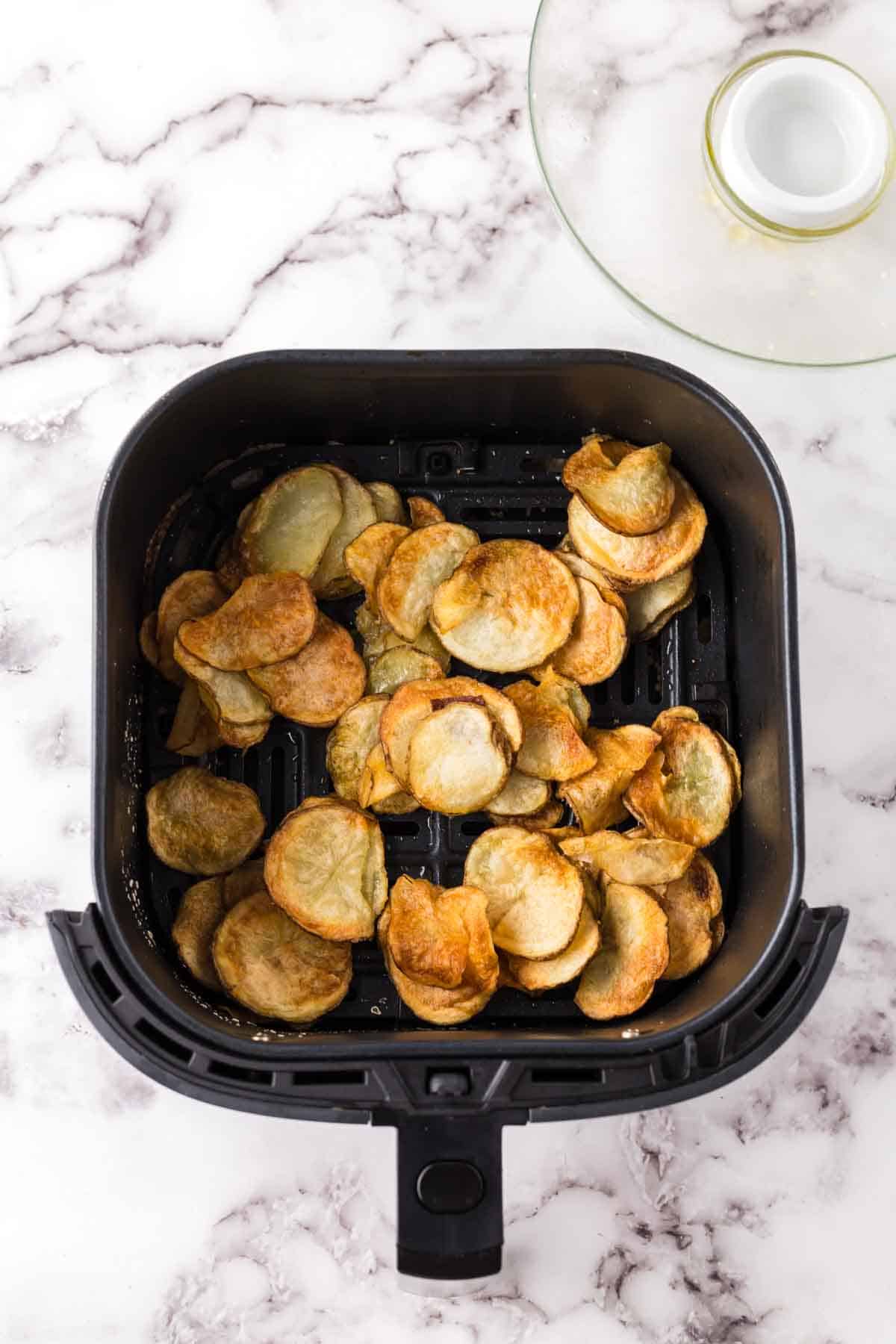 black air fryer basket with fried potato chips.
