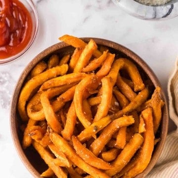 round wooden bowl with air fried sweet potato french fries with ketchup.
