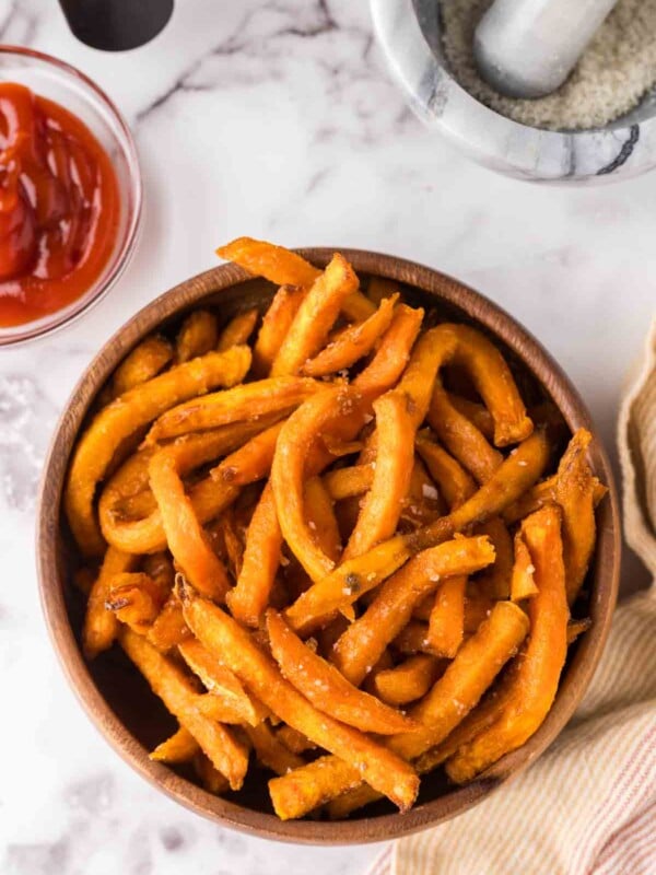 round wooden bowl with air fried sweet potato french fries with ketchup.