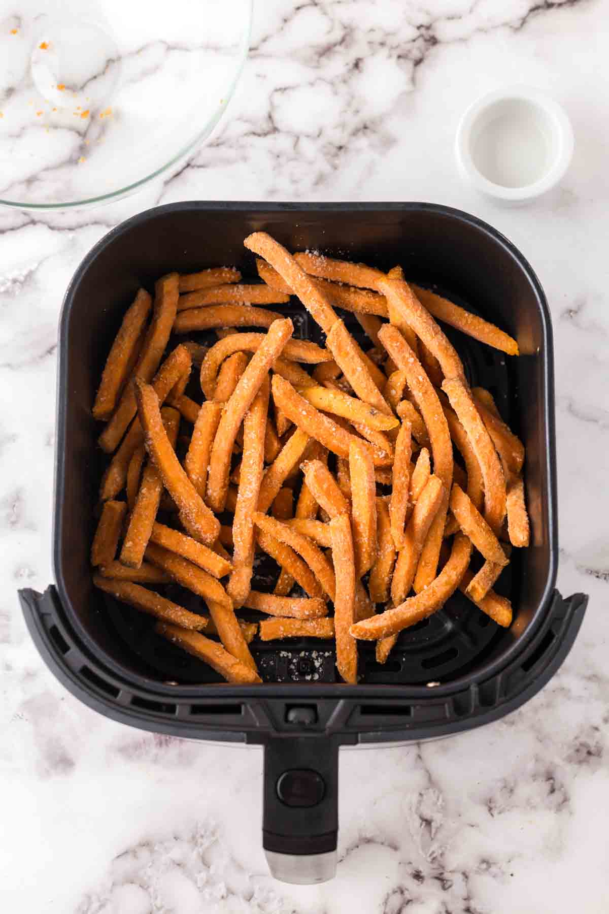 black air fryer basket of air fryer sweet potato fries.