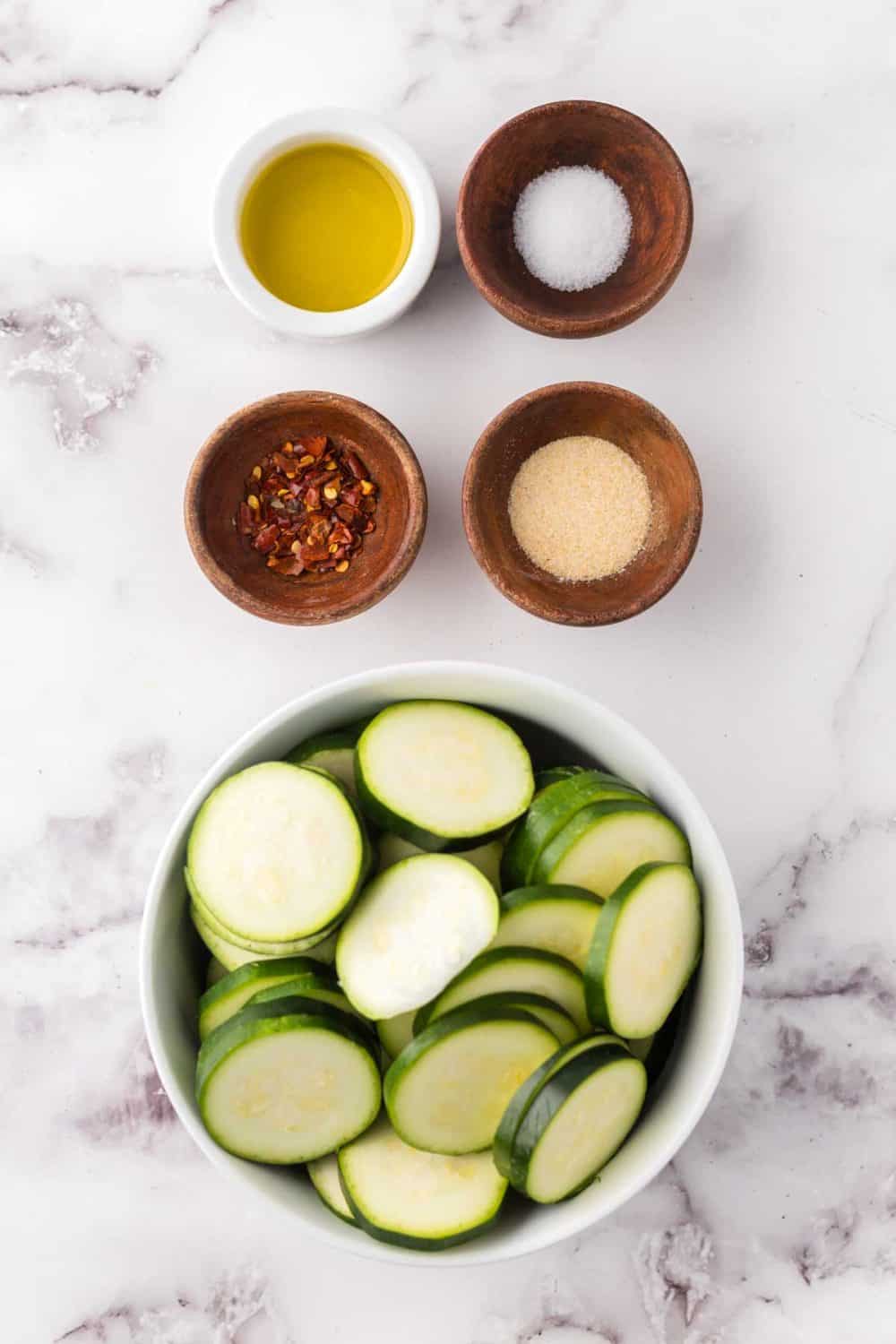 portion bowls each with raw ingredient to make air fryer zucchini.