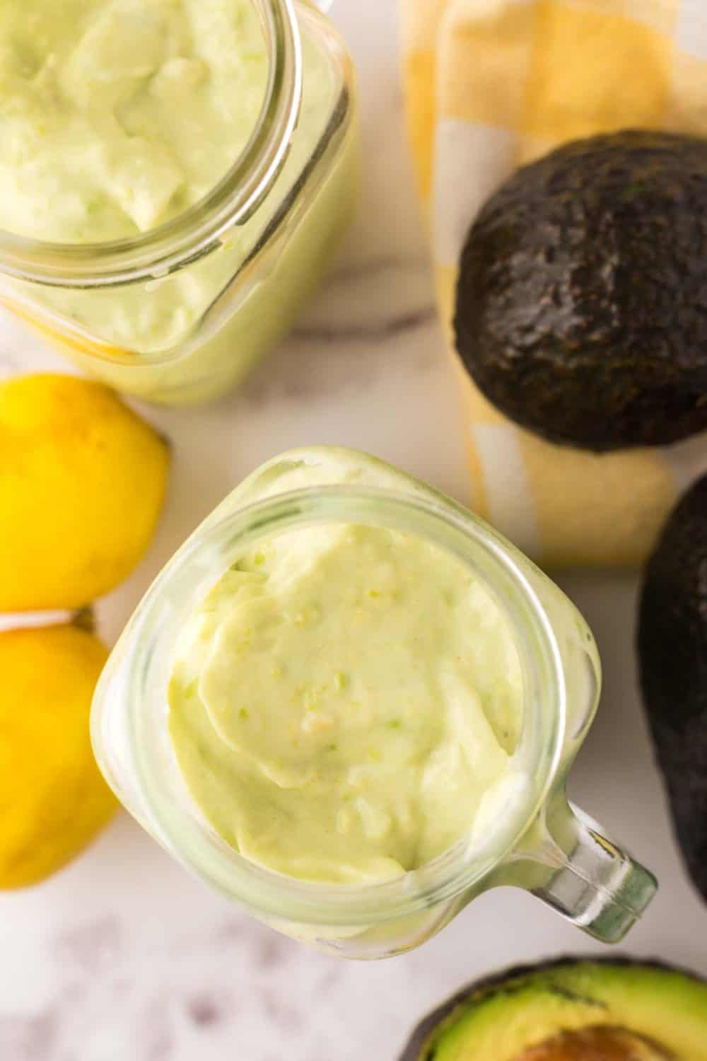 handled glass mason jar filled with avocado smoothie with fresh avocado lemon on the side.