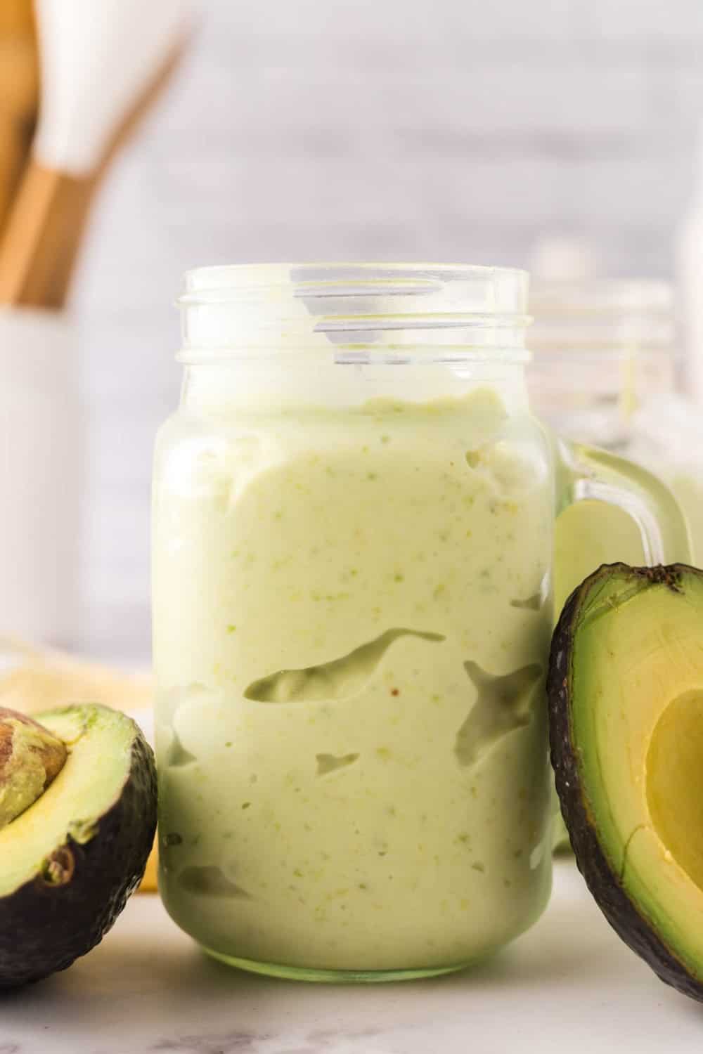 handled glass mason jar filled with avocado smoothie.