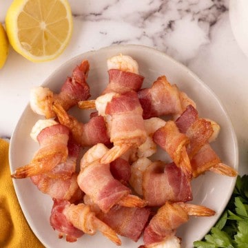 bacon wrapped shrimp recipe with lemons on a plate.
