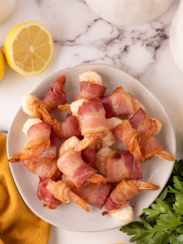 bacon wrapped shrimp recipe with lemons on a plate.