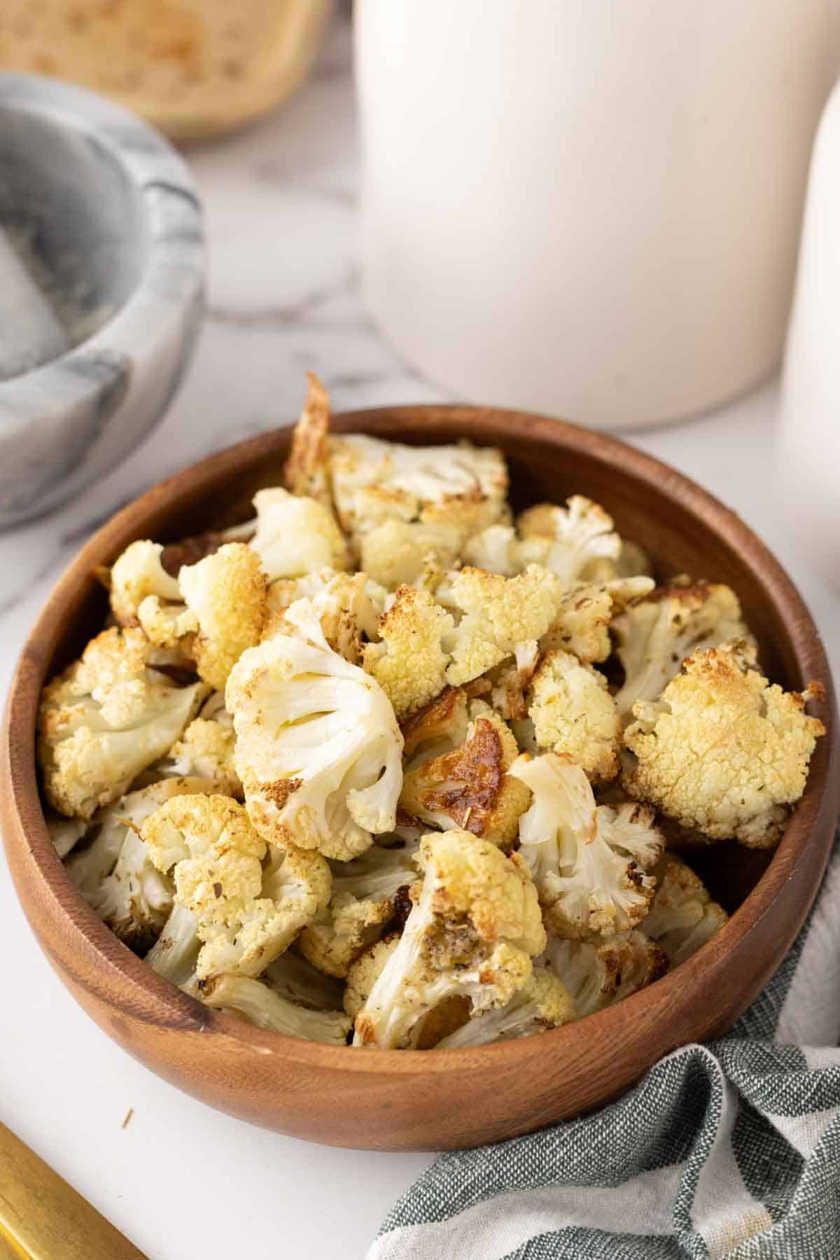 baked cauliflower florets in a wooden bowl.