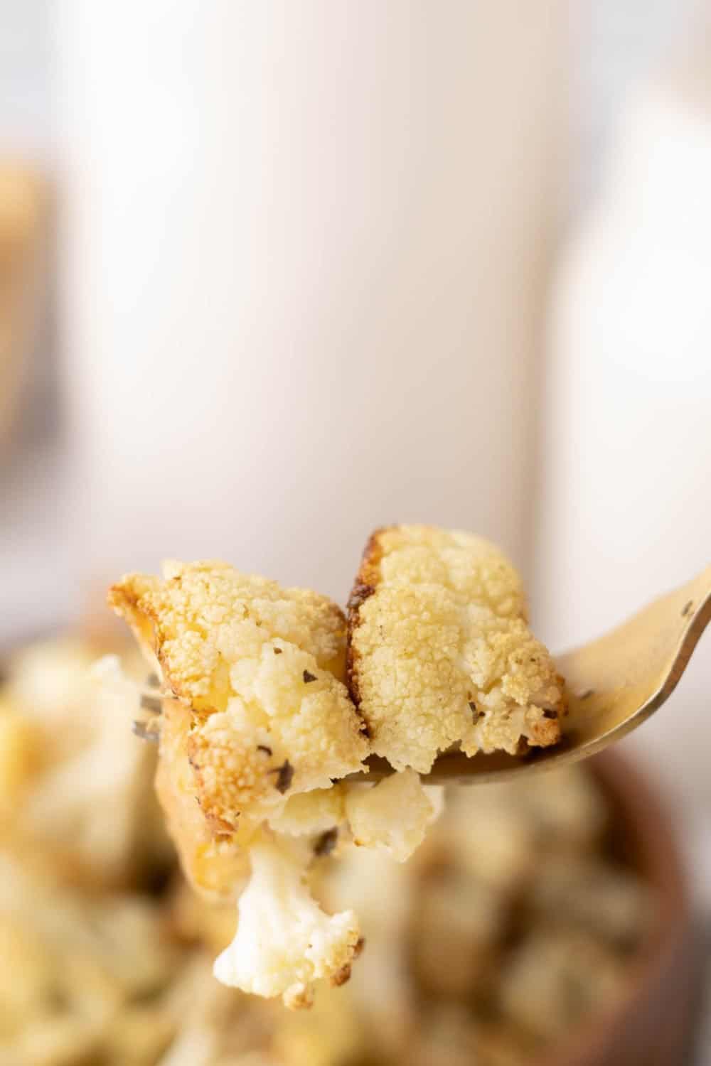 baked cauliflower florets on a golden fork.