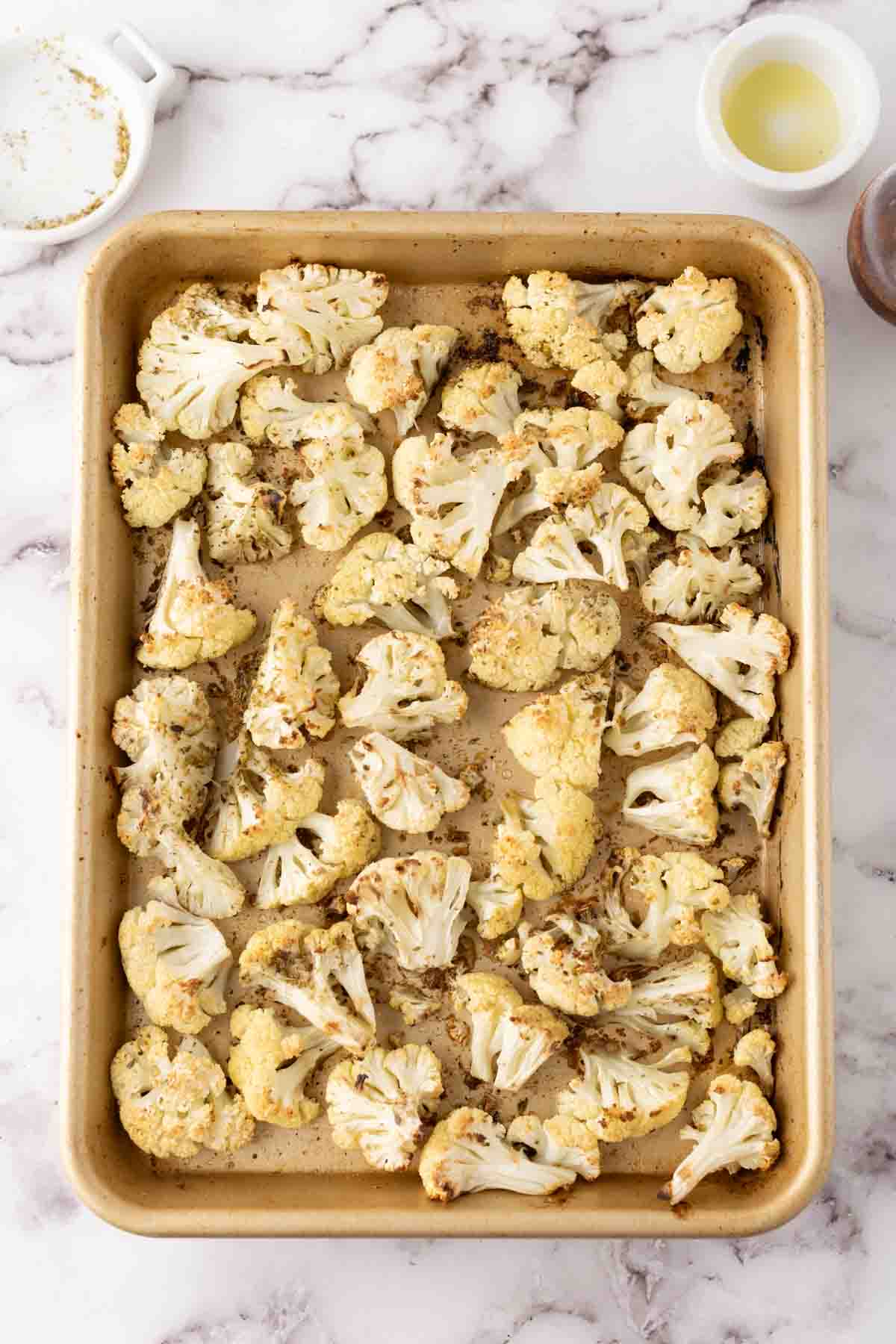 white cauliflower florets seasoned on a baking dish.