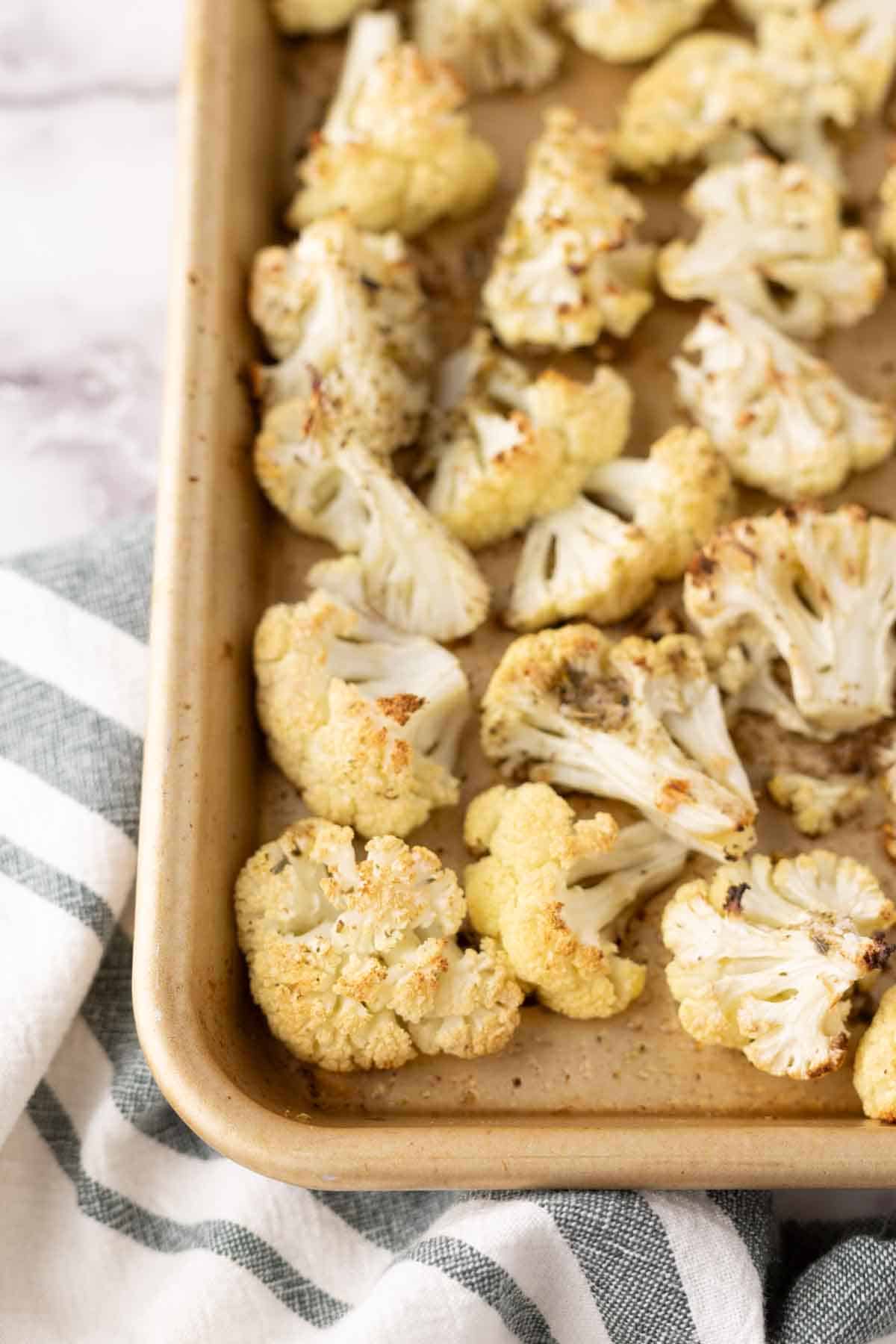 white cauliflower florets seasoned on a baking dish.