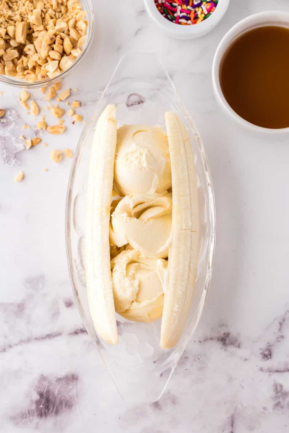 oval dish with banana split making in progress with bananas and vanilla ice cream.