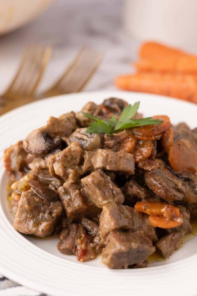 Beef Bourguignon Recipe served on a white plate with golden forks.