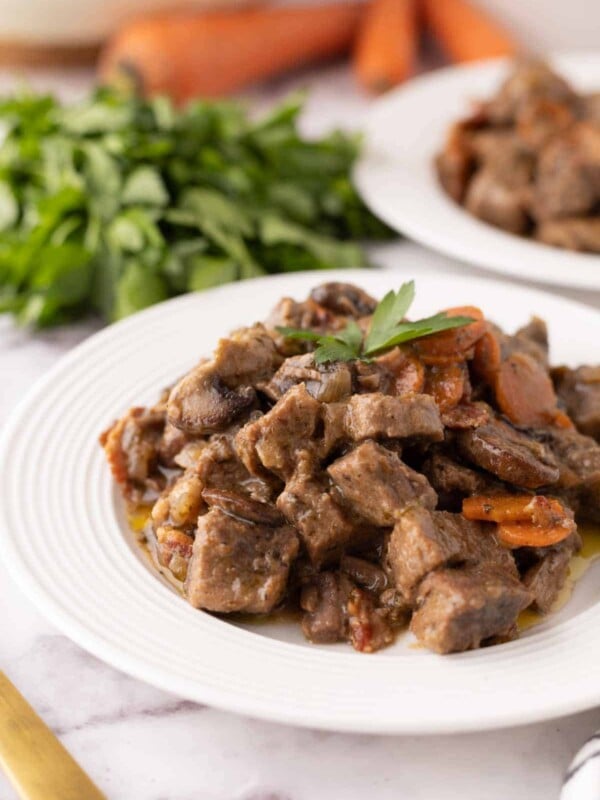 Beef Bourguignon Recipe served on a white plate with golden forks.