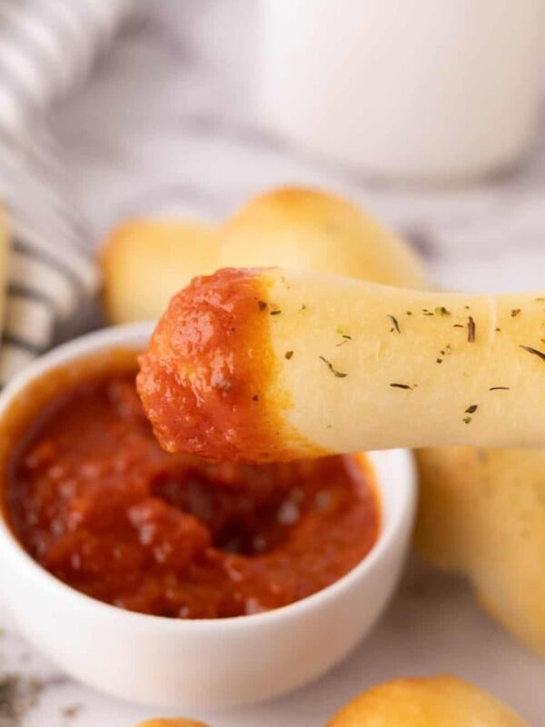 one bosco stick dipped into a small bowl of red sauce.