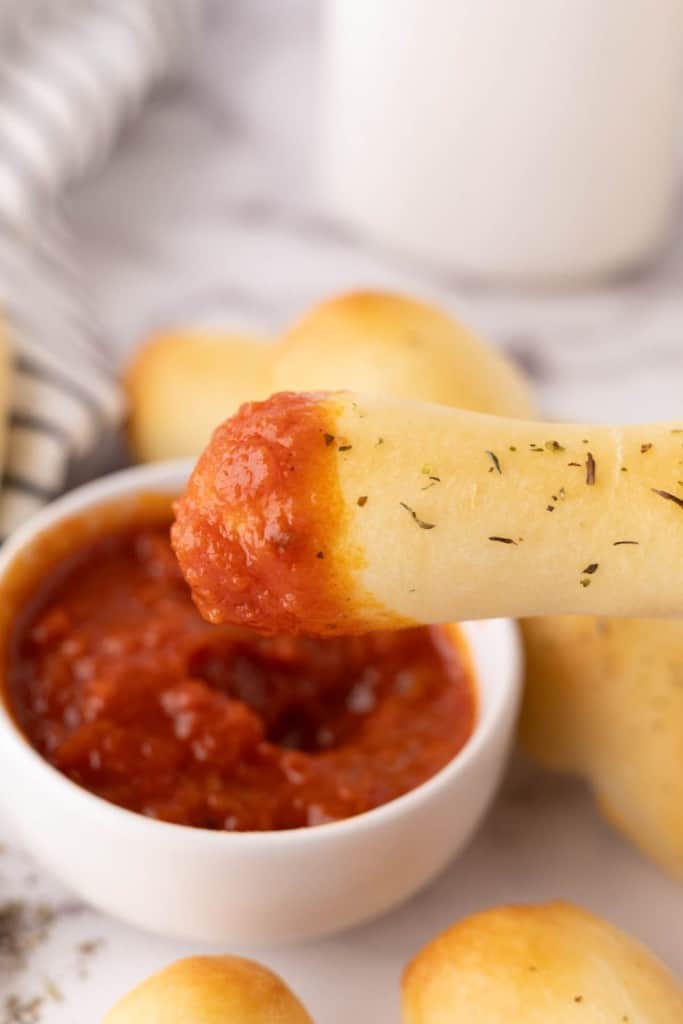 one bosco stick dipped into a small bowl of red sauce.