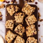 oat breakfast bars cut into square servings on a wooden board.