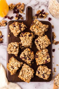 oat breakfast bars cut into square servings on a wooden board.
