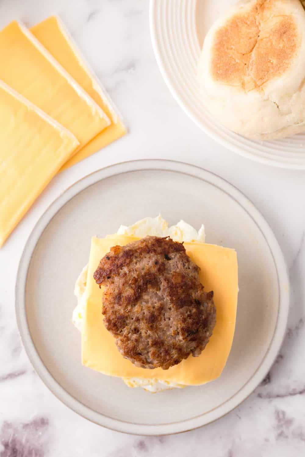 eggs and other ingredients to make a breakfast sandwich. on a plate.