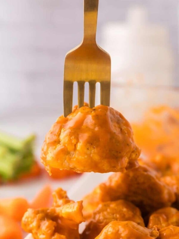 buffalo sauced cauliflower floret on a golden fork.