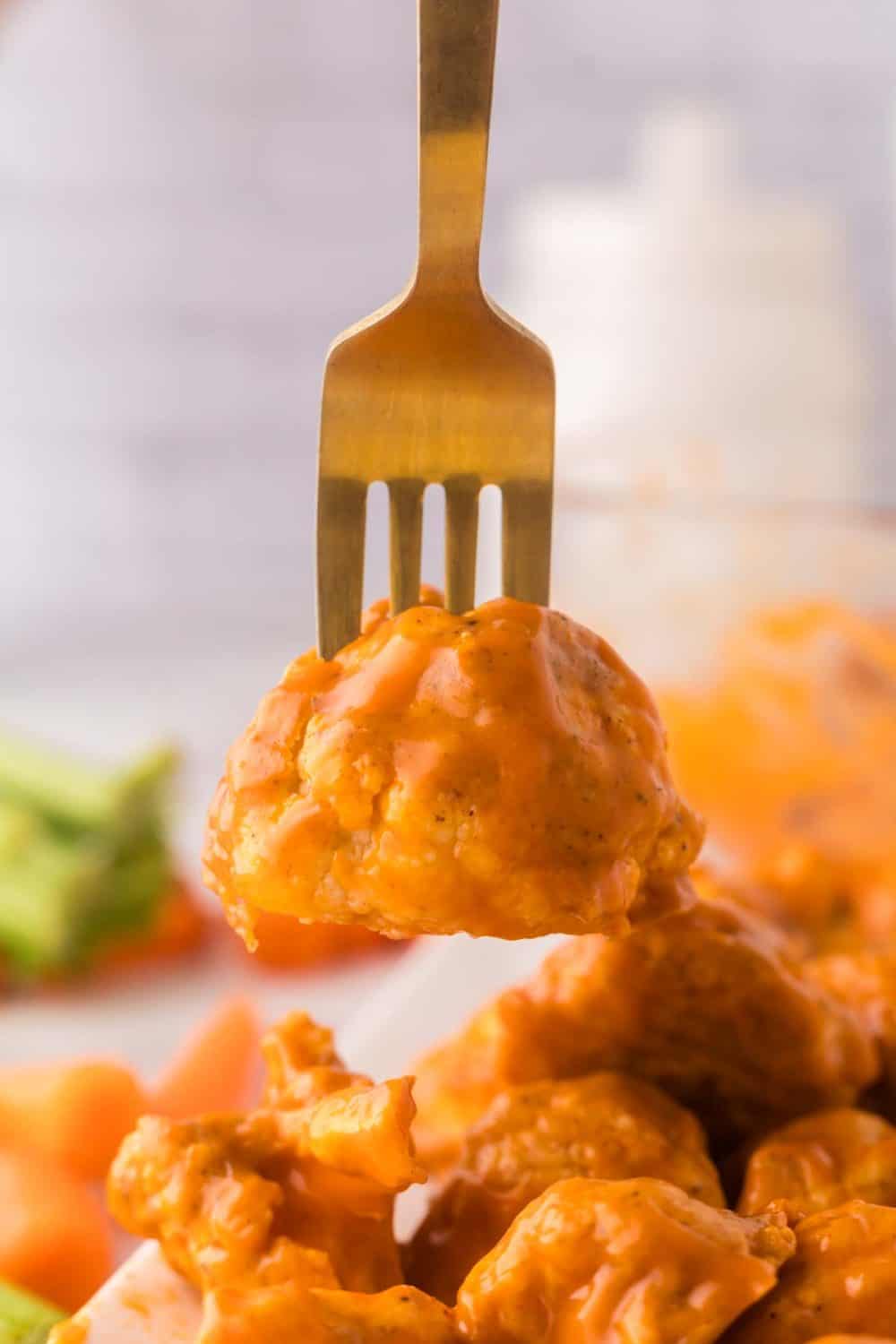 buffalo sauced cauliflower floret on a golden fork.