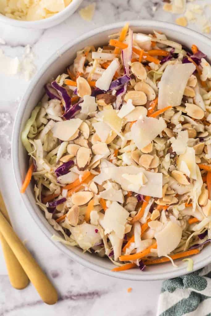 cabbage salad recipe in a white bowl with golden forks to the side.