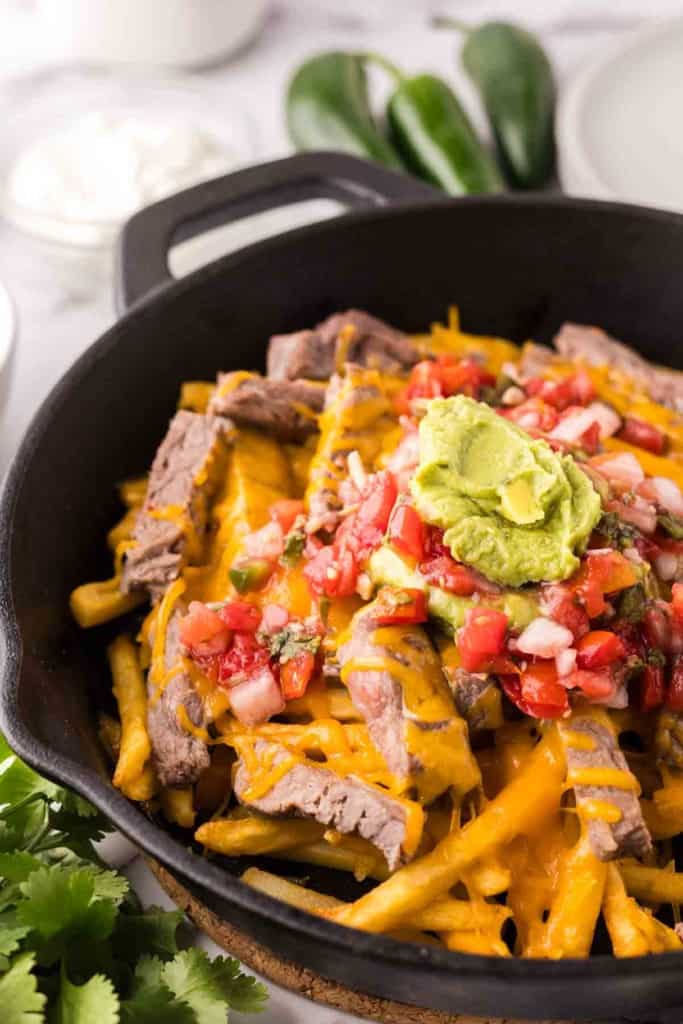 cast iron pan showing the progress of making carne asada fries recipe.