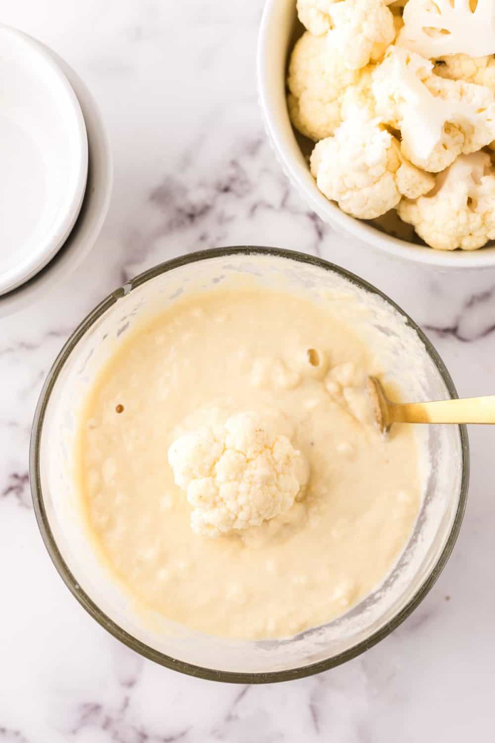 clear mixing bowl showing the progress of making cauliflower wing batter.