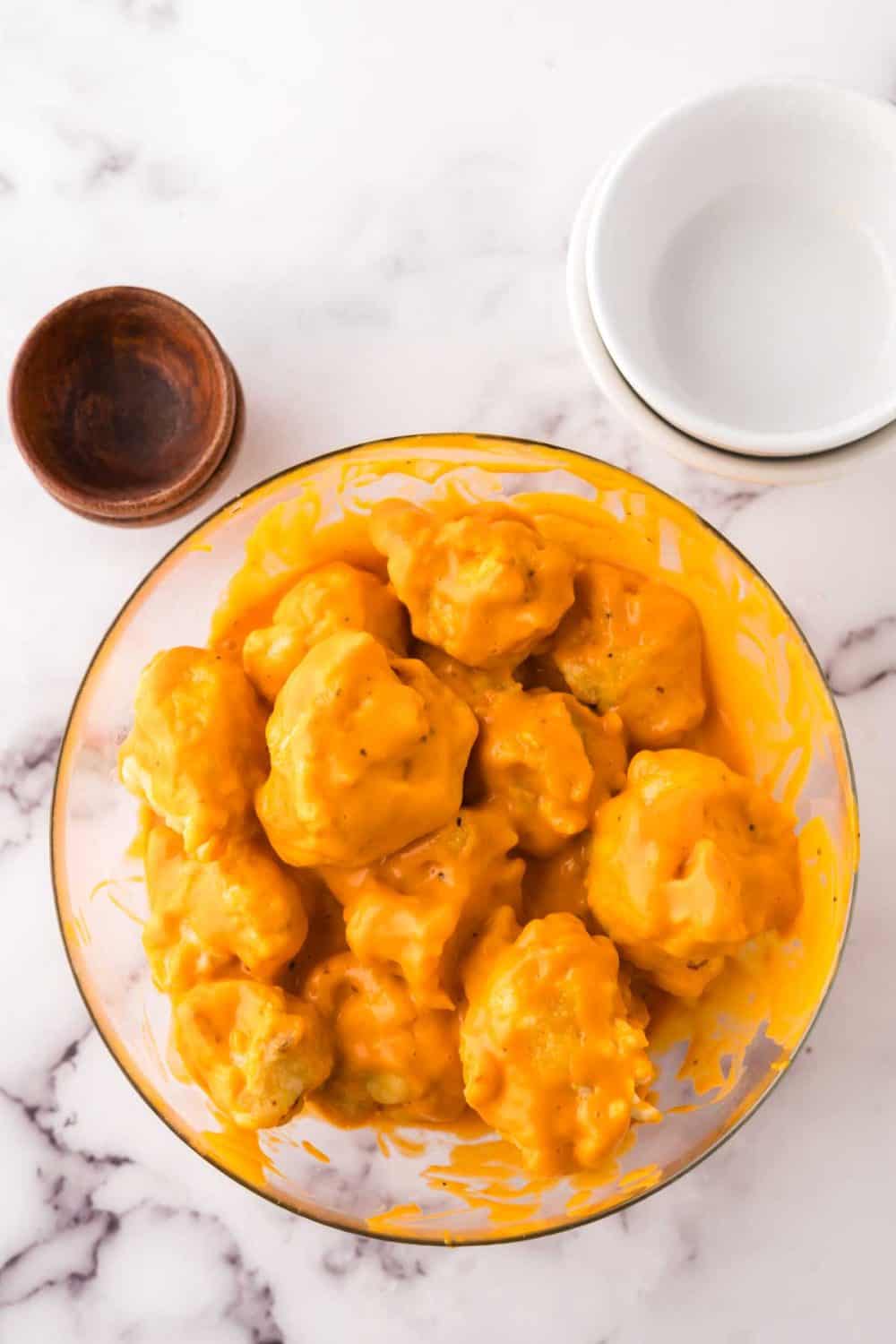 clear mixing bowl showing the progress of making cauliflower wings recipe.