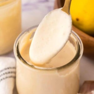 side view of homemade caesar dressing recipe in a small glass jar with a spoon