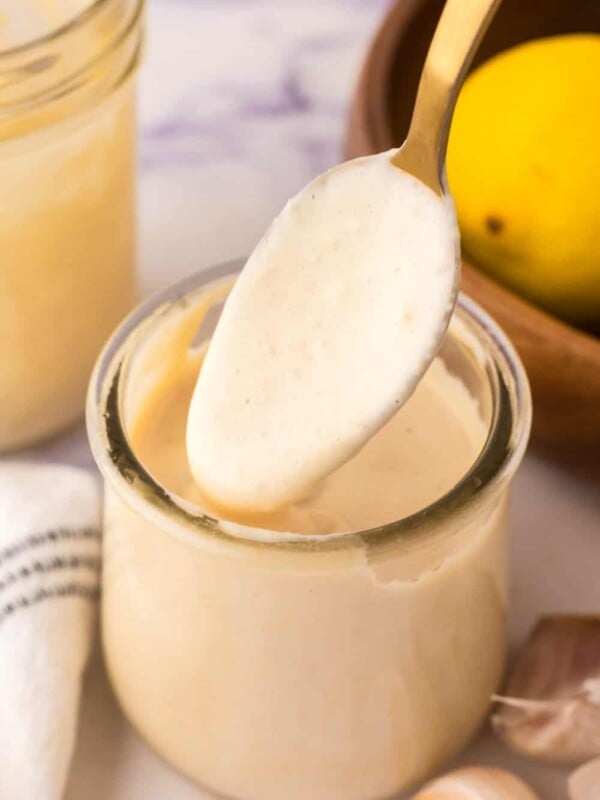 side view of homemade caesar dressing recipe in a small glass jar with a spoon