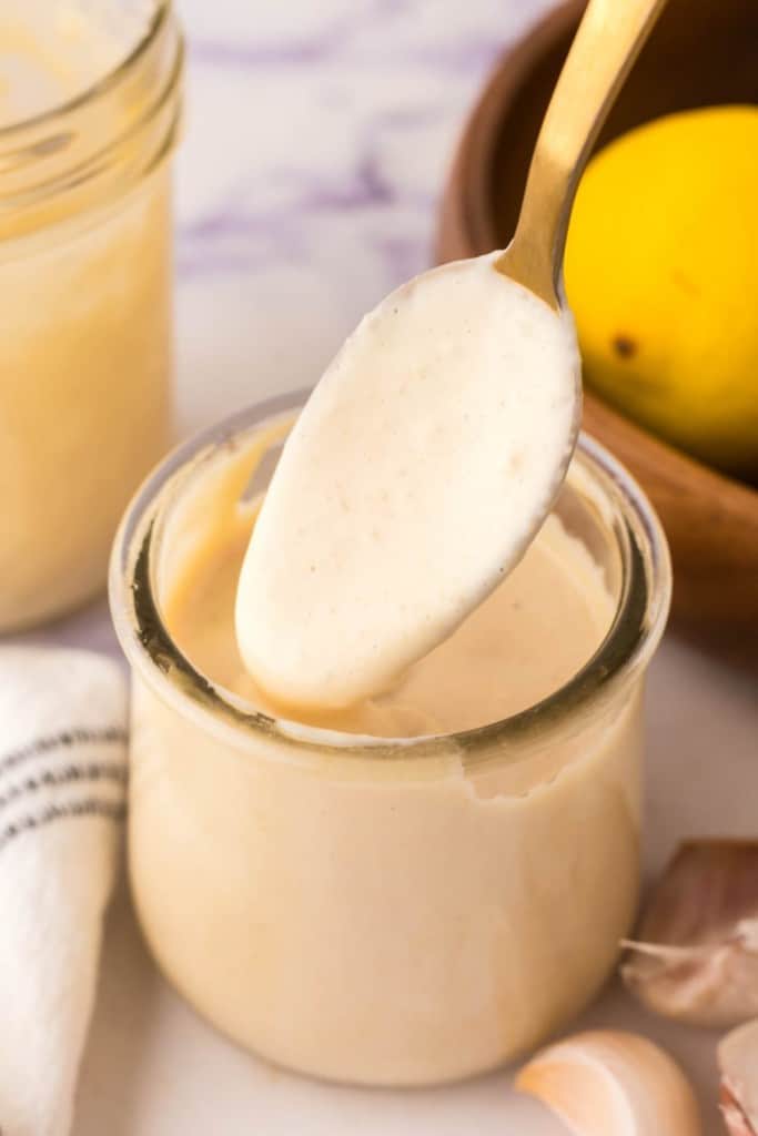 side view of homemade caesar dressing recipe in a small glass jar with a spoon
