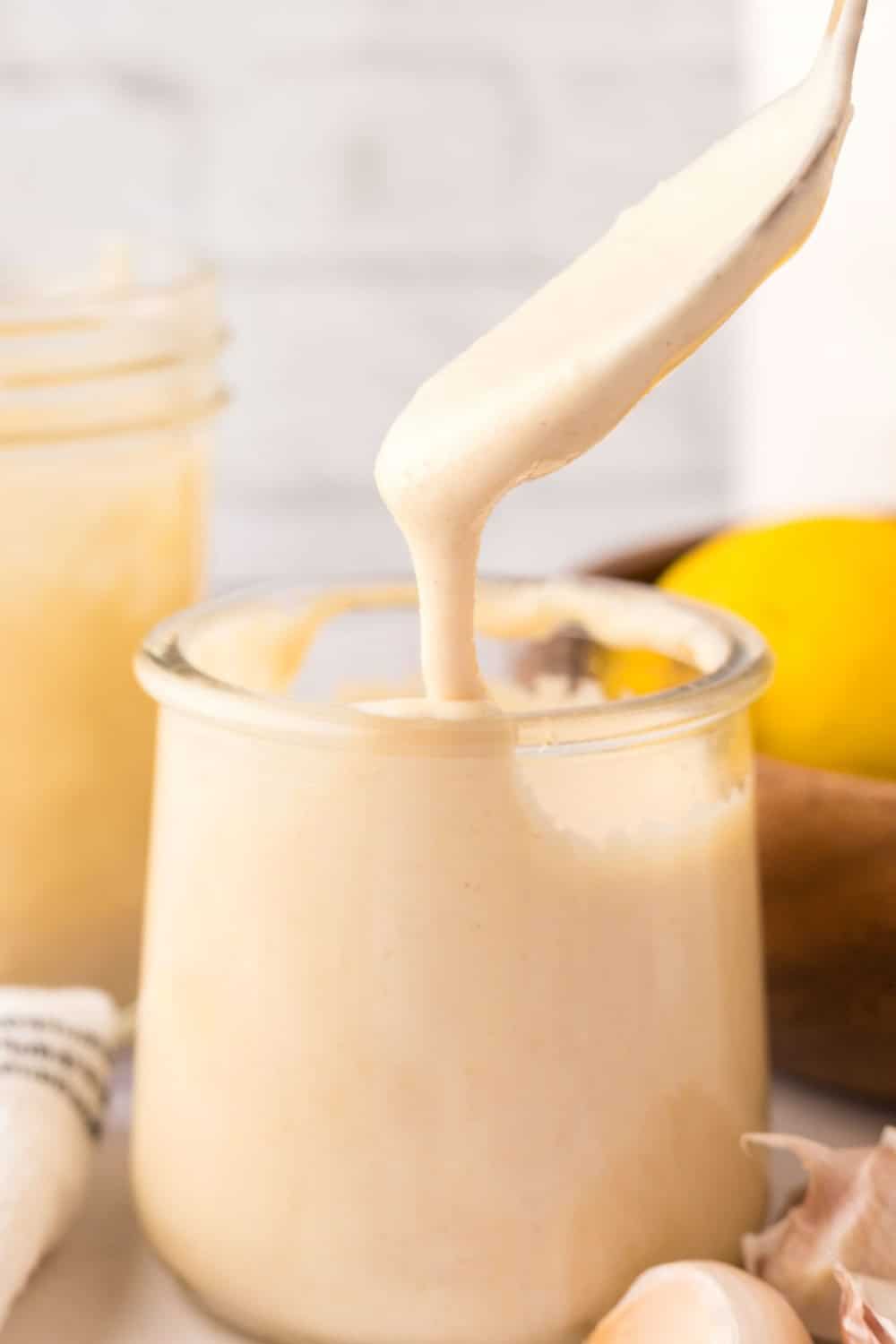 side view of homemade caesar dressing recipe in a small glass jar with a spoon