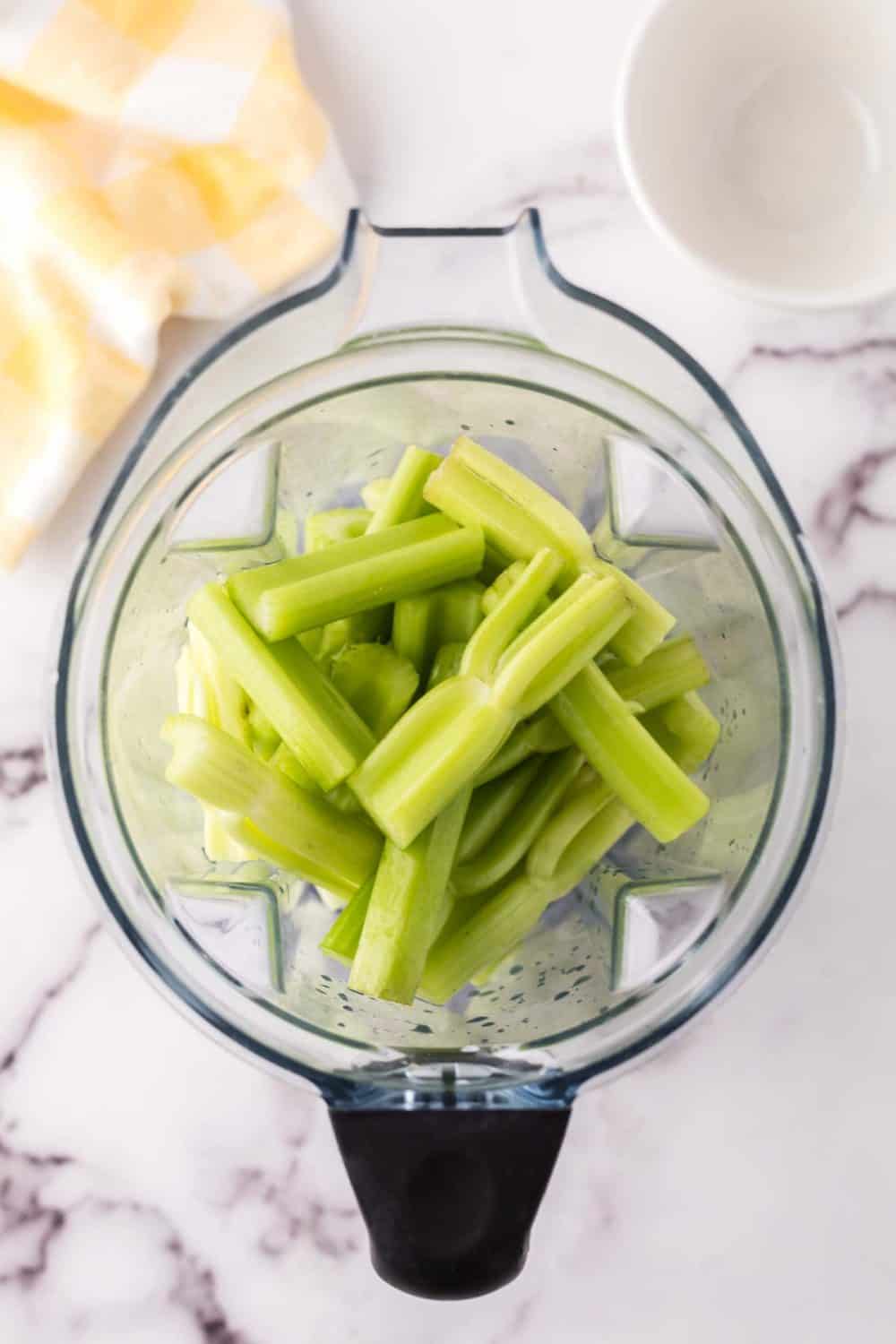 a blender with chopped celery in the pitcher.