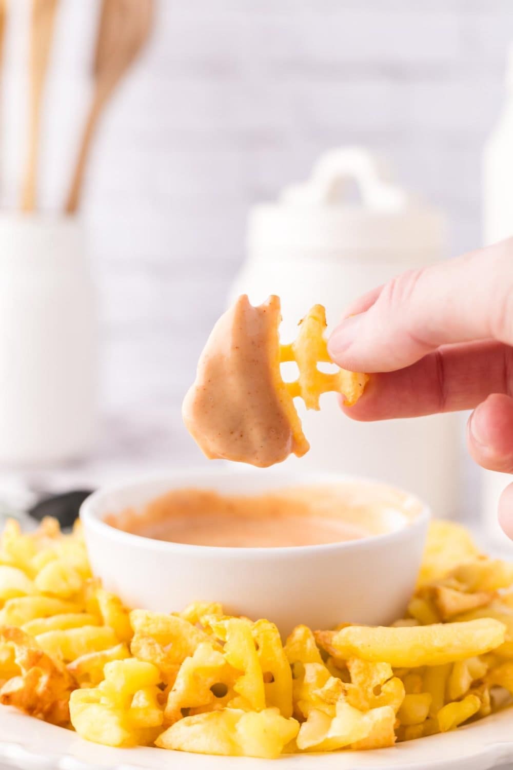 Chick-fil-A Sauce a small bowl with waffle fries all around it and a fry being dunked in.