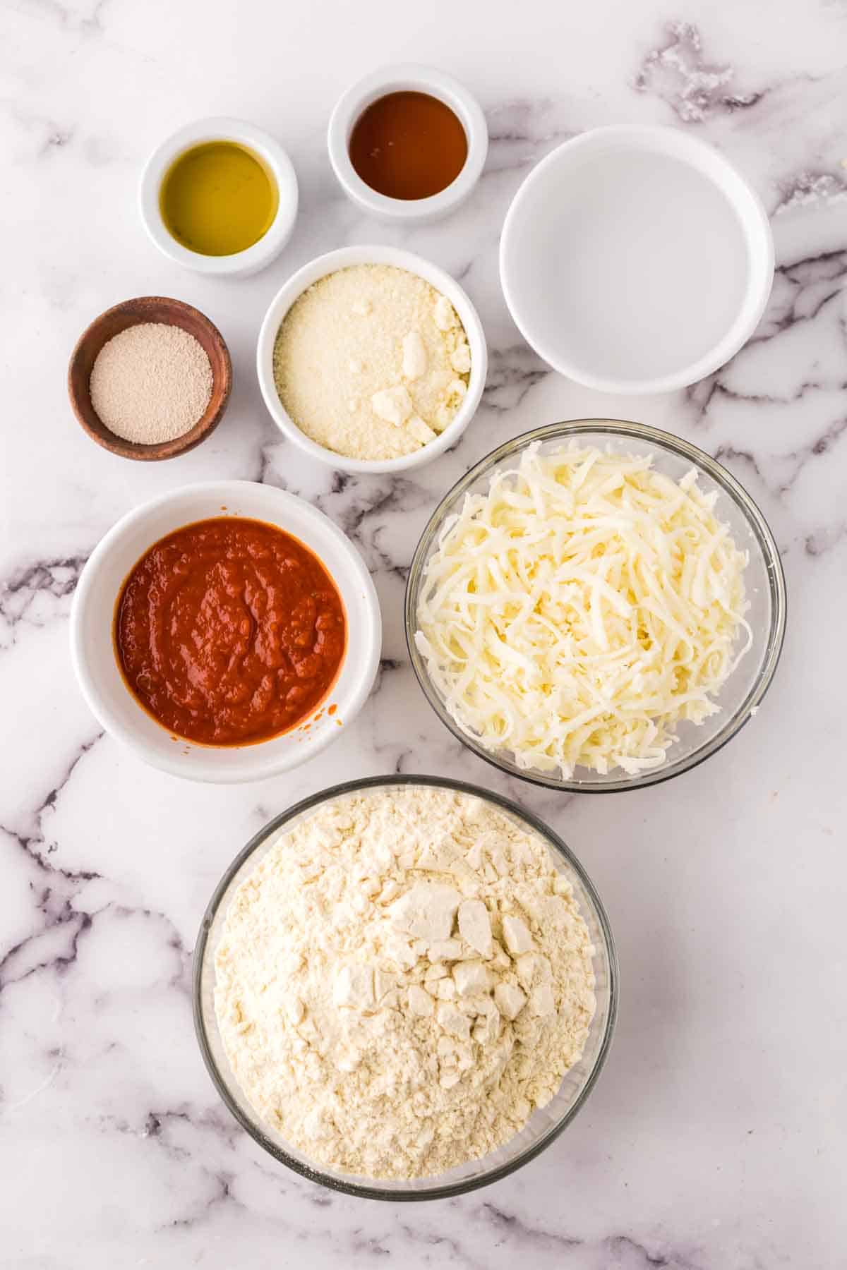 portion bowls each with raw ingredient to make cheese pizza recipe.